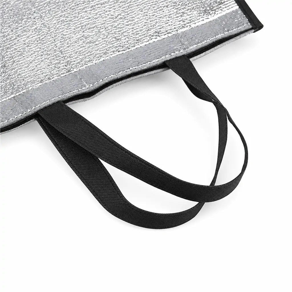 Two aluminum foil insulated bags with crinkled silver foil bodies, one with red binding and handles and one with black, standing on a kitchen counter